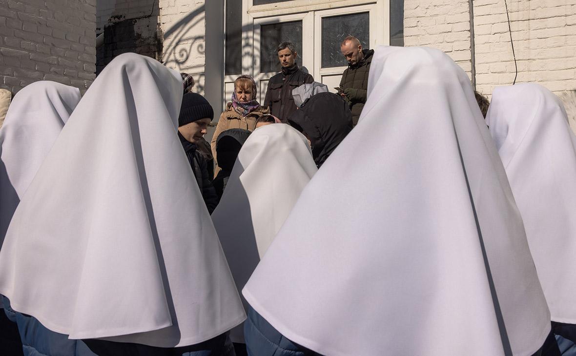 Верующие и монахини Украинской православной церкви стоят у двери здания, блокируя украинским чиновникам вход на территорию Киево-Печерской лавры