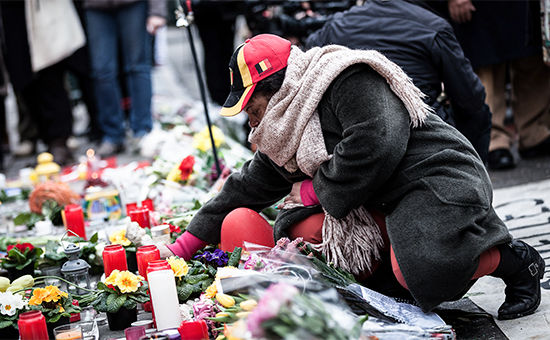 Женщина кладет цветы на мемориал в память о жертвах терактов в Бельгии


