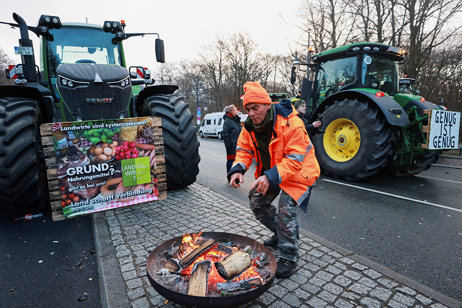 Фермер греется у огня во время акции протеста в Берлине, 15 января