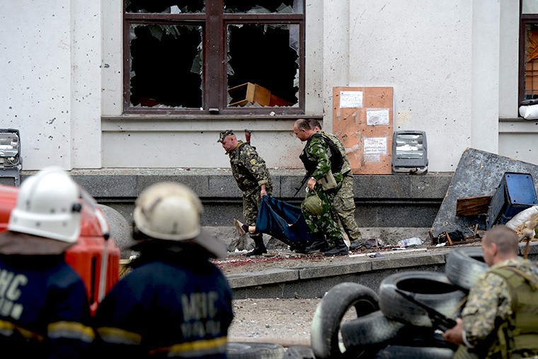Ополченцы несут тело погибшего в результате авианалета ВВС Украины на здание обладминистрации в Луганске 3 июня.