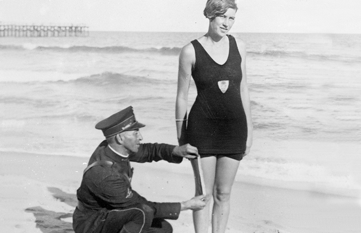 <p>Полицейский измеряет длину шорт посетительницы пляжа. Это не постановочное фото, а действительность: некоторые страны пытались вводить законы, которые регламентировали степень открытости купальника</p>