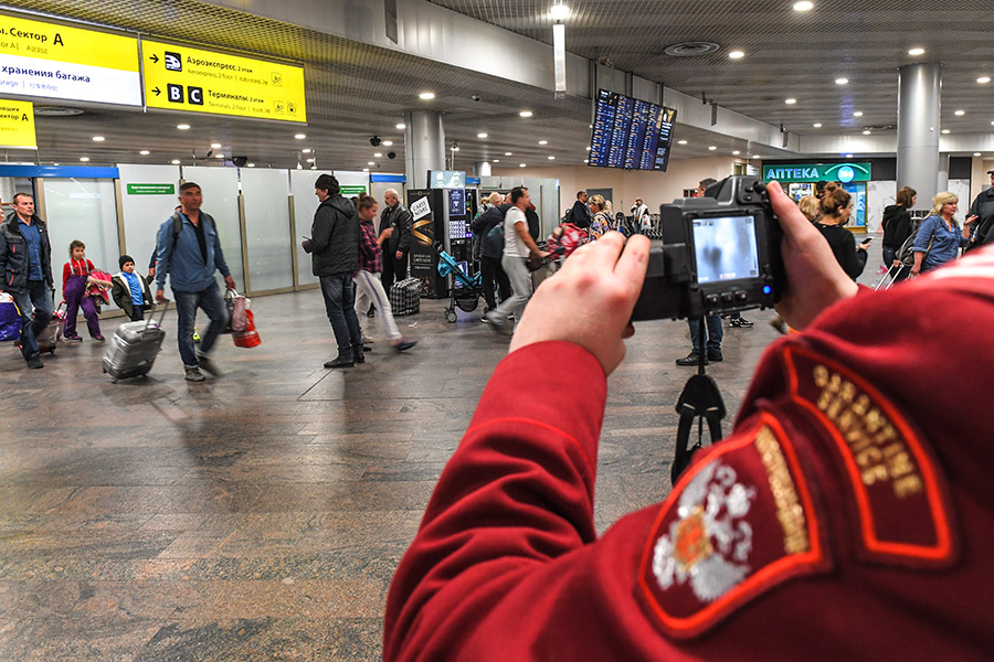Сотрудник санитарно-карантинного пункта дистанционно измеряет температуру пассажирам, прибывшим в московский аэропорт Шереметьево
