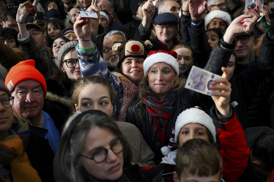 Посетители с банкнотами в руках на мясном аукционе в Лондоне.