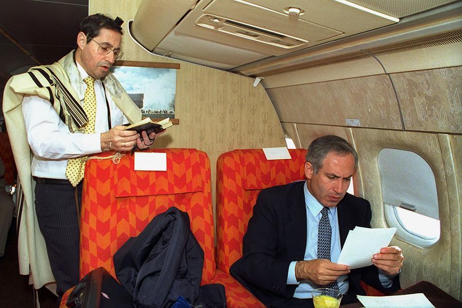 Замминистра иностранных дел Израиля Биньямин Нетаньяху (справа) просматривает&nbsp;бумаги, пока правительственный секретарь Эльяким Рубинштейн читает утренние молитвы во время полета из Нью-Йорка в Вашингтон, 1989 год
