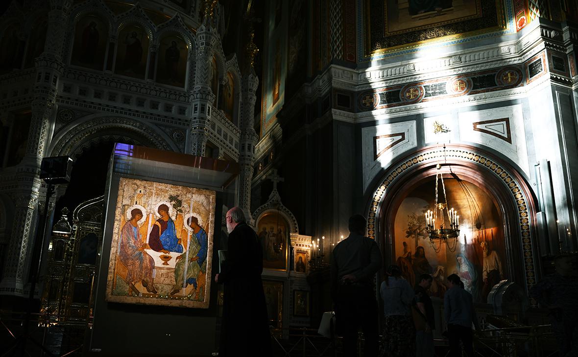 Священнослужитель возле иконы &laquo;Святая Троица&raquo; Андрея Рублева