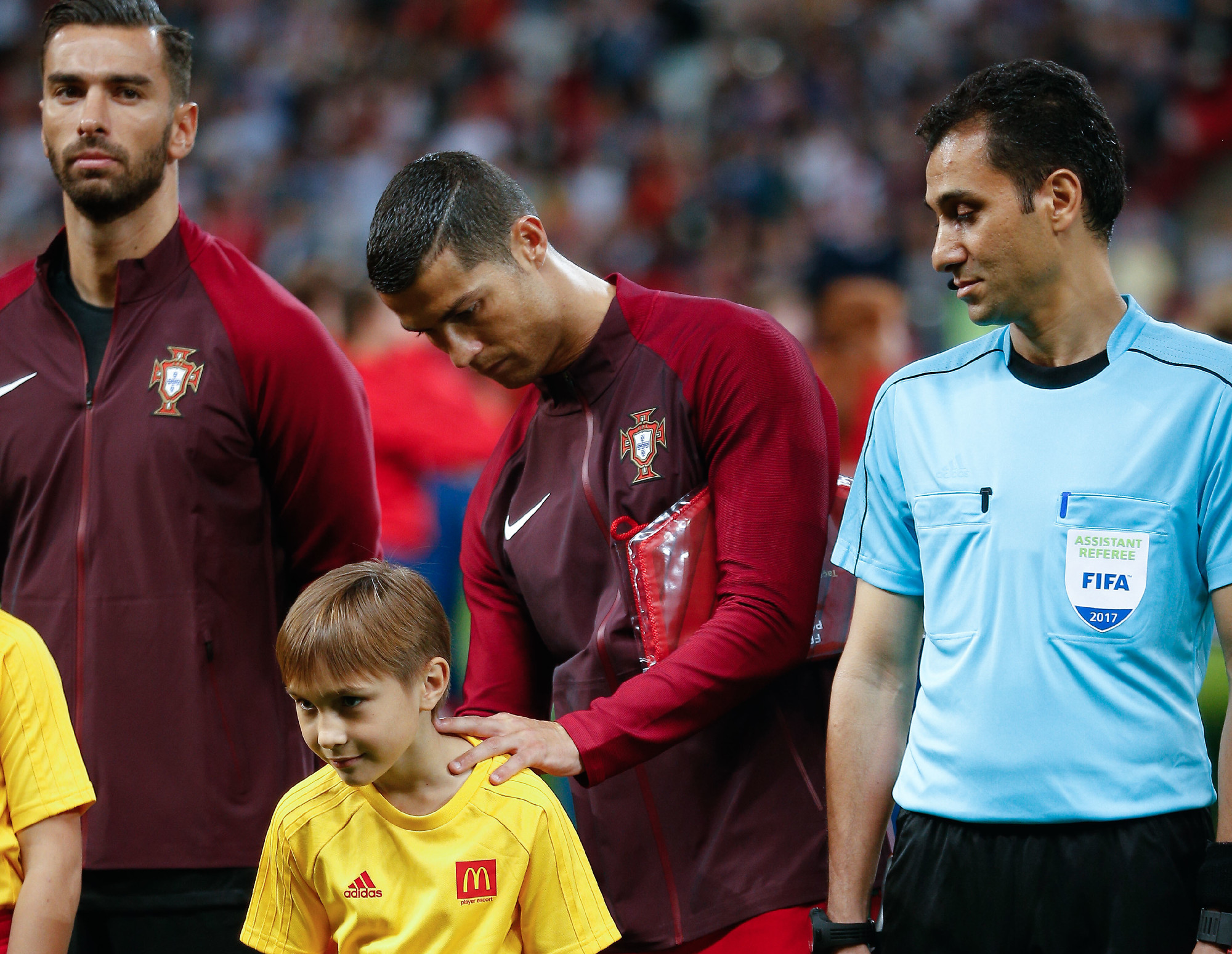 Капитан сборной Португалии Криштиану Роналду ставит автограф на футболке мальчика, который вывел его на поле в полуфинале с командой Чили