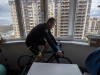 Мужчина тренируется на балконе своего дома во время пандемии коронавируса
