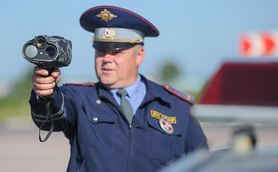 Сотрудник ГИБДД фиксирует скорость движения автомобилей