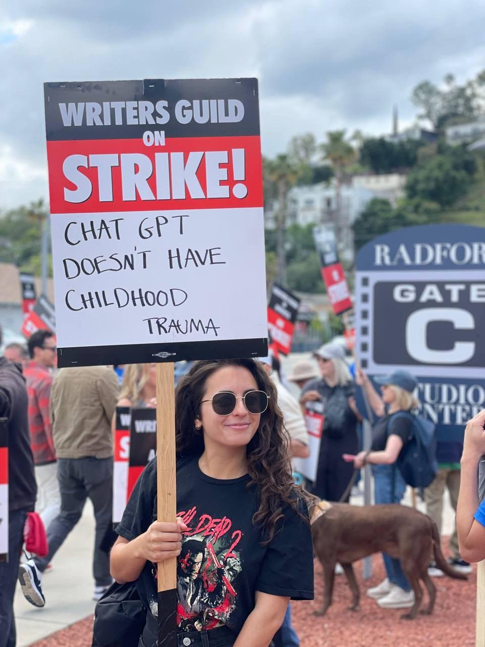 Участница забастовки с плакатом «У ChatGPT нет детской травмы»