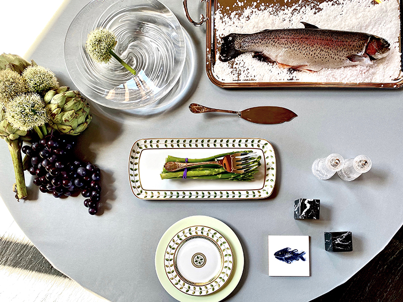 Тарелки из коллекций Constance, Cronos Amande — все Bernardaud; кубок для шампанского 100 Points, блюдо Poissons Combattants, набор из двух мельниц Peugeot, стакан для воды Wingen — все Lalique; сервировочная ложка Malmaison, сервировочные нож и вилка для рыбы Marly, поднос Albi — все Christofle