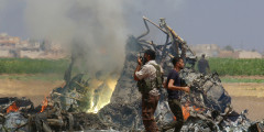 Мужчины осматривают обломки российского вертолета, который был сбит повстанцами в сирийской провинции Идлиб