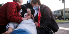 Две участницы демонстрации оказывают помощь оппозиционеру, пострадавшему при столкновении с силовиками