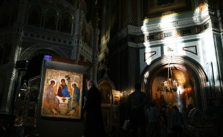 Священнослужитель возле иконы «Святая Троица» Андрея Рублева