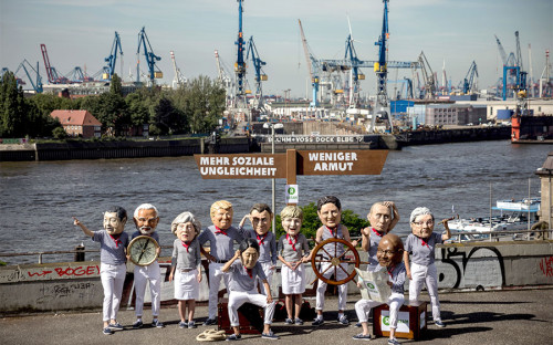 <p>Активисты Oxfam (международное объединение из 17 организаций, работающих в более чем 90 странах, целью деятельности которых является решение проблем бедности) в масках с изображением лиц глав государств под указателем с надписью &laquo;Больше социальной несправедливости&raquo; и &laquo;Меньше бедности&raquo;</p>
