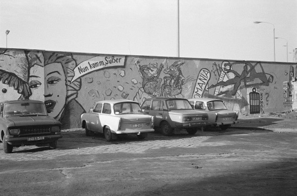 На фото: парковка в ГДР с автомобилями Wartburg 353 и Trabant, 26 декабря 1989 года.
Trabant производился с ноября 1957 по апрель 1991 и был назван в честь советского спутника, который запустили за месяц до старта производства. Несмотря на высокопарное название, в простонародье автомобиль называли «гоночной картонкой», «пластиковым бомбардировщиком» и «местью Хонеккера» (генсека социалистической партии ГДР). Из-за низкой цены это был самый распространенный автомобиль в ГДР, всего за 34 года было произведено около 3,7 млн машин. Однако в очереди на его покупку можно было простоять более десятилетия, из-за чего даже появилась шутка: «Почему в ГДР не грабят банки? Потому что машину после ограбления нужно было бы ждать 12 лет!»
Wartburg 353 начали производиться в 1966 году. Помимо соцблока, его экспортировали в Бельгию, Финляндию, Великобританию и даже ЮАР, несмотря на то, что «зазоры между панелями кузова с одной стороны вполне могли отличаться от зазоров с другой на толщину пальца». К 1991 году, когда производство было остановлено, было выпущено более 1,2 млн Wartburg 353 и 353W.