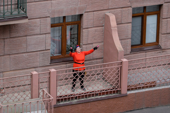 Жительница многоквартирного жилого дома на улице летчика Ивана Федорова в Химках во время зарядки на балконе своей квартиры