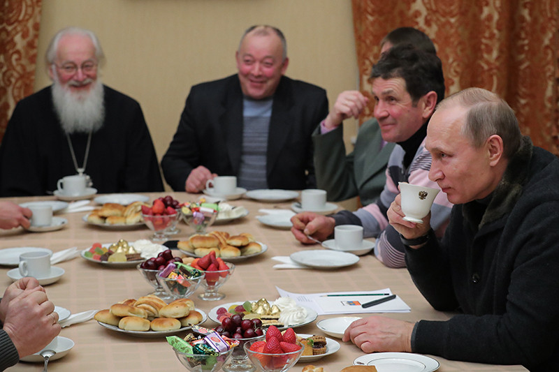 Президент России Владимир Путин (справа) во время встречи с рыбаками после Рождественского богослужения в Свято-Юрьевом монастыре в Великом Новгороде. Слева направо на дальнем плане - митрополит Новгородский и Старорусский Лев и губернатор Новгородской области Сергей Митин. 7 января 2016 года