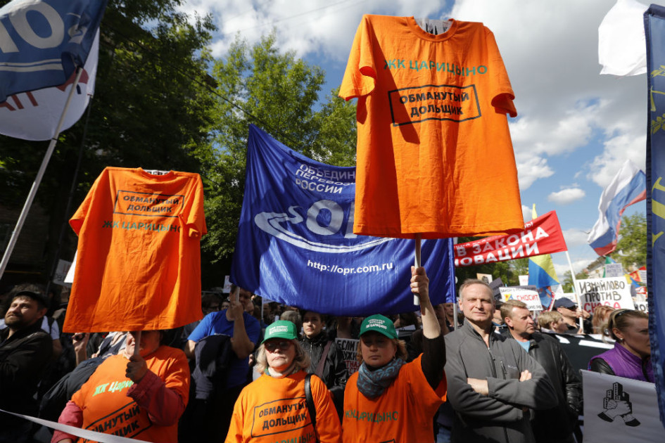 Участники митинга шли под флагами столичных районов, с красно-белыми строительными лентами, плакатами и транспарантами
